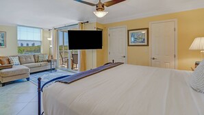 A bedroom with a large bed, a ceiling fan, a TV, and a balcony with a view. - IN-UNIT WASHER/DRYER | WALK-IN CLOSET | FREE WIFI | KING BED + QUEEN SLEEPER | STEPS TO BONITA BEACH (Bonita Springs)