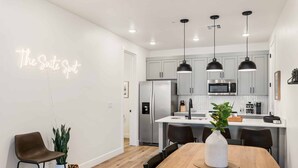 Une cuisine moderne avec des meubles gris, des appareils en acier inoxydable et des luminaires suspendus.