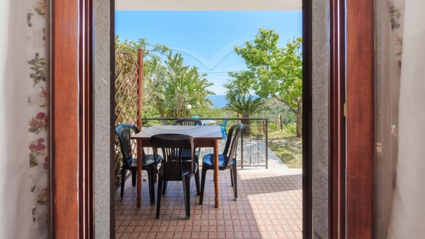 Un patio al aire libre con mesa y sillas, vistas a zonas verdes y un cielo despejado.