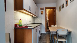 A compact kitchen with a sink, countertop, and a dining area with a table and chairs. - Arslan Homes3 (Muğla)
