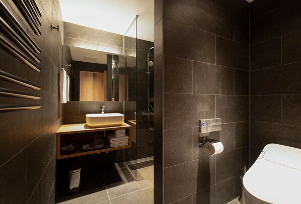 Une salle de bain moderne avec une douche à parois de verre, un lavabo avec un miroir et des toilettes.
