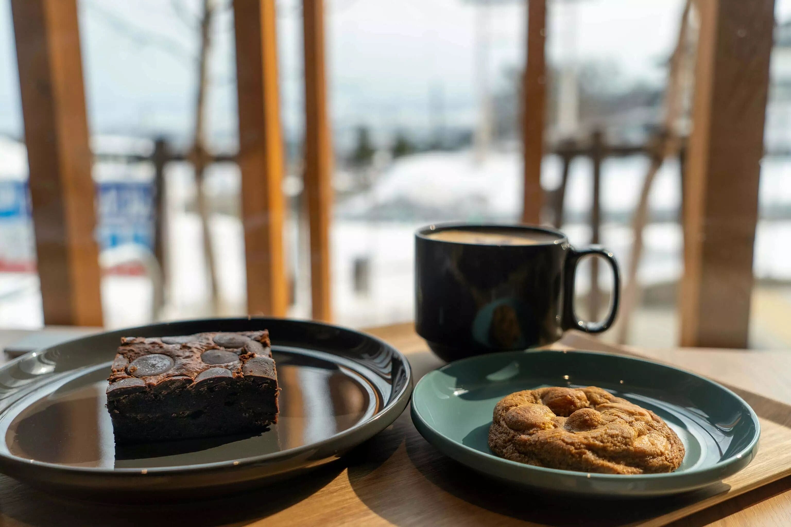 A dessert tray with a slice of chocolate cake and a cookie on a wooden table.