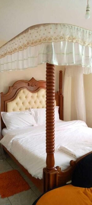A bed with a wooden headboard, white bedding, and a canopy with lace detailing. - Stay.Plus Harlequin Studio Apartments (Nairobi)