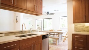 Una cucina moderna con mobili in legno, lavastoviglie e zona pranzo con tavolo e sedie.