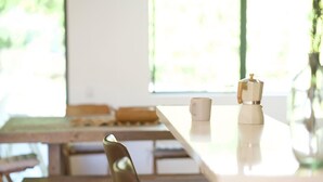 Un tavolo da pranzo in legno con una macchina da caffè bianca e due tazze bianche.