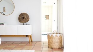 Un soggiorno moderno con un divano bianco, un tavolino rotondo in legno, un cesto di vimini e uno specchio appeso al muro.