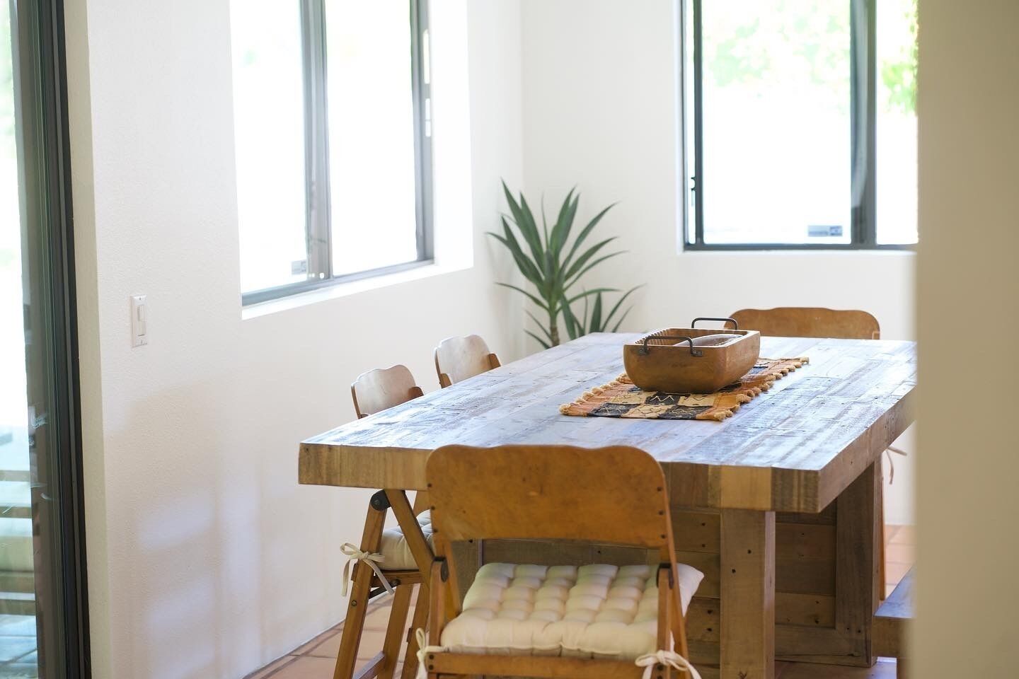 A dining area with a wooden table, cushioned chairs, and a woven placemat.
