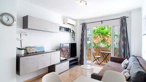 A modern living space with a dining area, a sofa, a TV, and a balcony with plants.