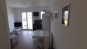 Un espace de vie compact comprenant une kitchenette, un coin repas et un téléviseur.