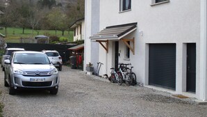 Une allée de gravier mène à un bâtiment blanc doté d’un garage et d’un porche abrité.