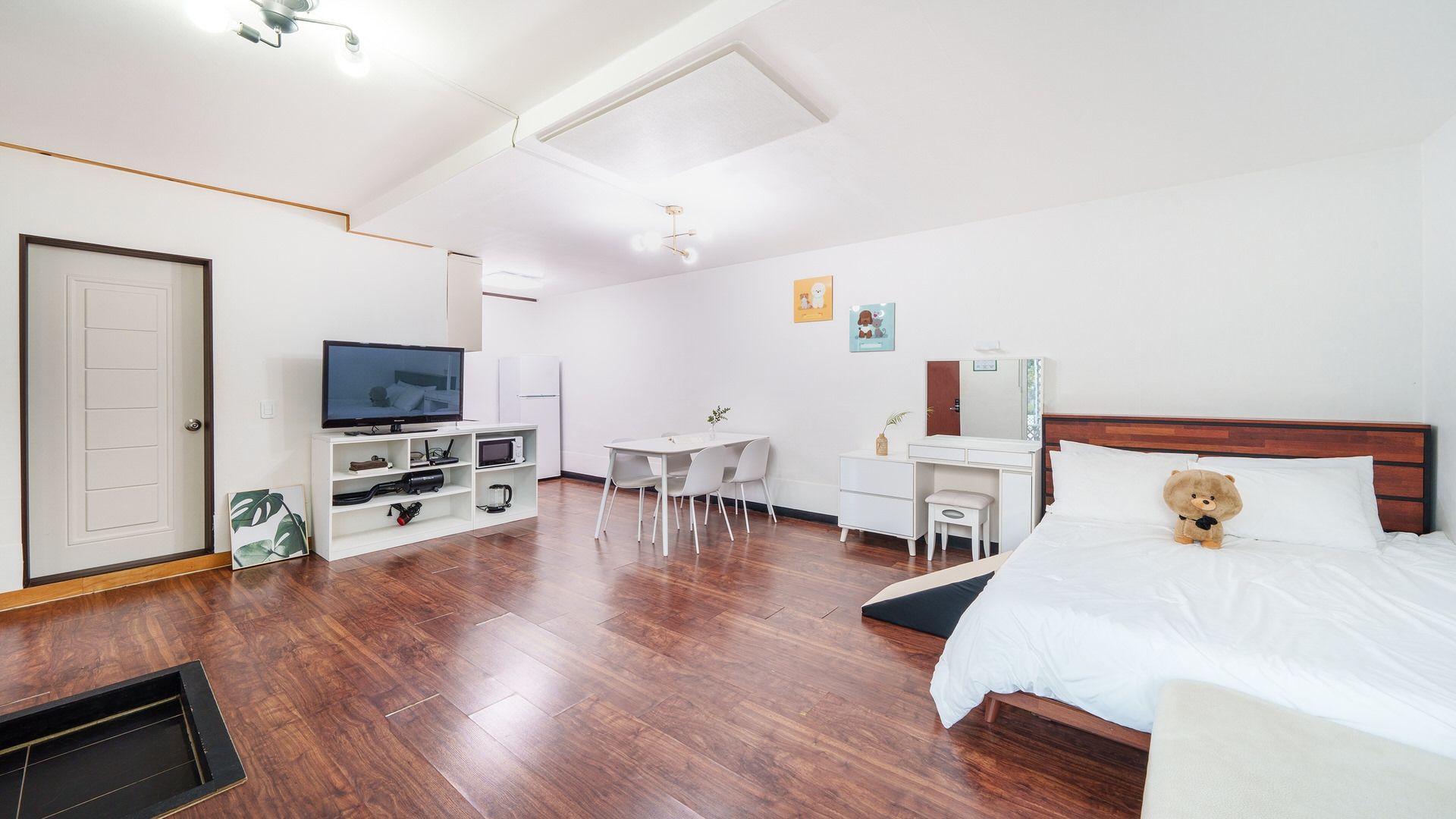 A hotel room with a bed, a desk, a television, and a small seating area.
