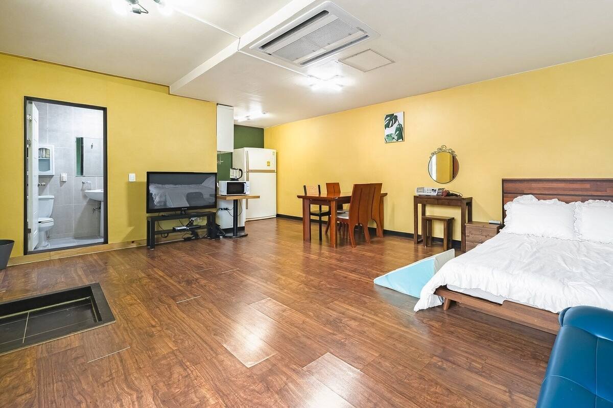 Une chambre d’hôtel équipée d’un lit, d’une télévision, d’un bureau, d’une chaise, d’un four à micro-ondes et d’une petite kitchenette.