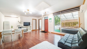 Una sala moderna con un sofá, una mesa de comedor con sillas, un televisor y una zona de cocina.