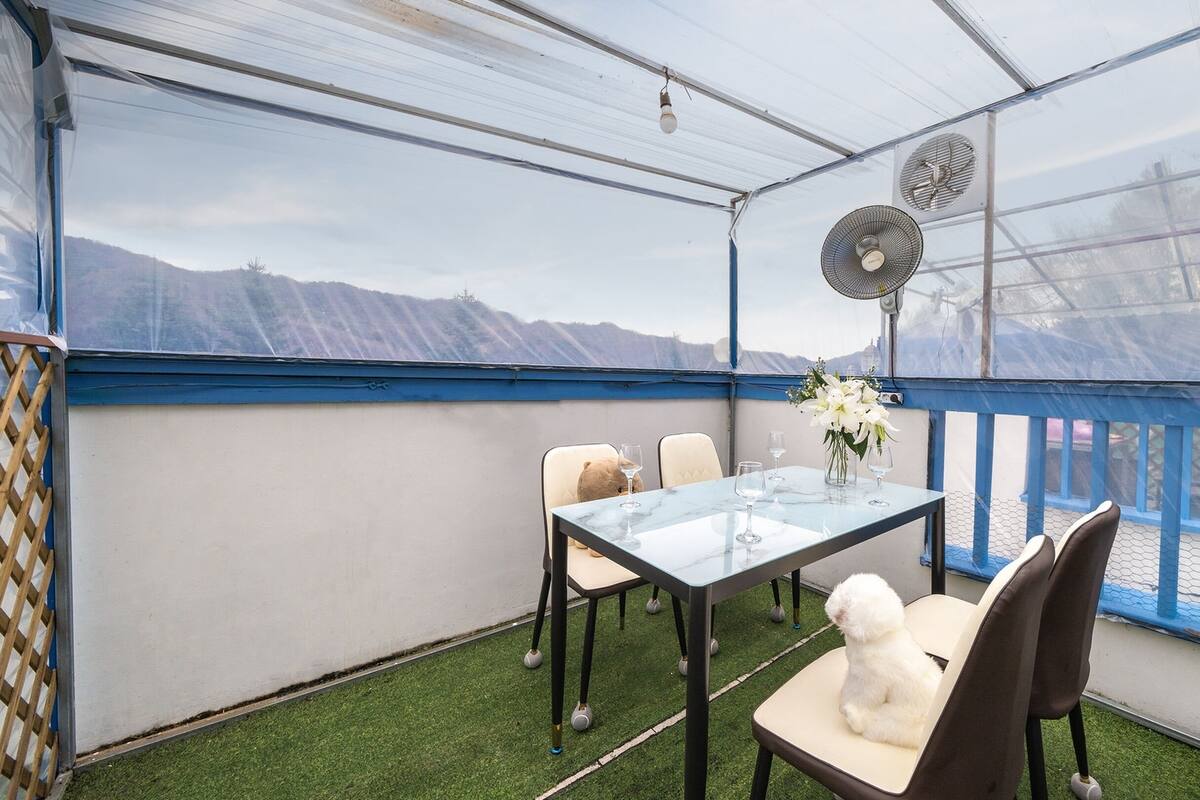 Une terrasse couverte avec une table, des chaises et un ours en peluche.