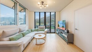 A modern living room with a sectional sofa, a coffee table, and a TV on a wooden cabinet. - Chuncheon Dogandstay (Chuncheon)