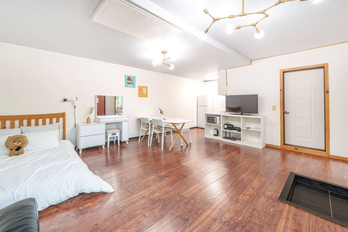 Une chambre à coucher avec un lit en bois, un bureau, une chaise, une télévision et une armoire.