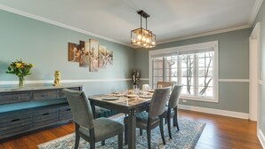 A dining area with a wooden table set for four, surrounded by chairs, a patterned rug, and a modern chandelier. - Bike & Kayak: Lakefront Prospect Heights Home (Prospect Heights)