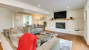 A living room with a fireplace, a television mounted above it, and two sofas. - Bike & Kayak: Lakefront Prospect Heights Home (Prospect Heights)