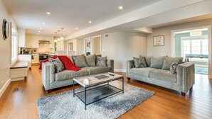 A spacious living room with two grey sofas, a coffee table, and a kitchen in the background. - Bike & Kayak: Lakefront Prospect Heights Home (Prospect Heights)