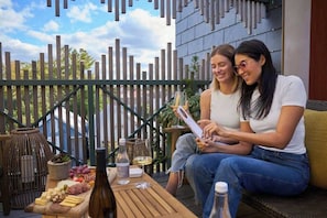 Dos personas sentadas en un banco de madera al aire libre, con una mesa frente a ellas.
