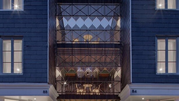 Un bâtiment moderne doté d’un atrium central, de grandes fenêtres et d’une entrée sécurisée par un portail.