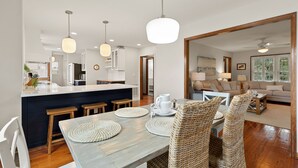 Cocina moderna con una isla central, taburetes de madera e iluminación colgante.