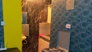 Una cocina compacta con estufa a gas, un lavamanos y un refrigerador.