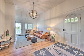 A spacious living room with a leather sofa, a coffee table, and a chandelier.