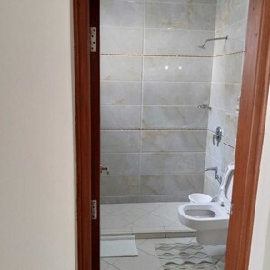 A bathroom with a toilet, shower, and tiled walls.