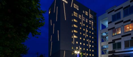 A multi-story hotel with a modern design, featuring a prominent 'GRIDS' sign on the facade.