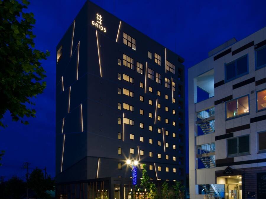 A multi-story hotel with a modern design, featuring a prominent 'GRIDS' sign on the facade.