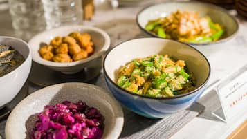 Uma mesa com diversos pratos, incluindo uma tigela de vegetais verdes, uma tigela de vegetais roxos e uma tigela de macarrão.