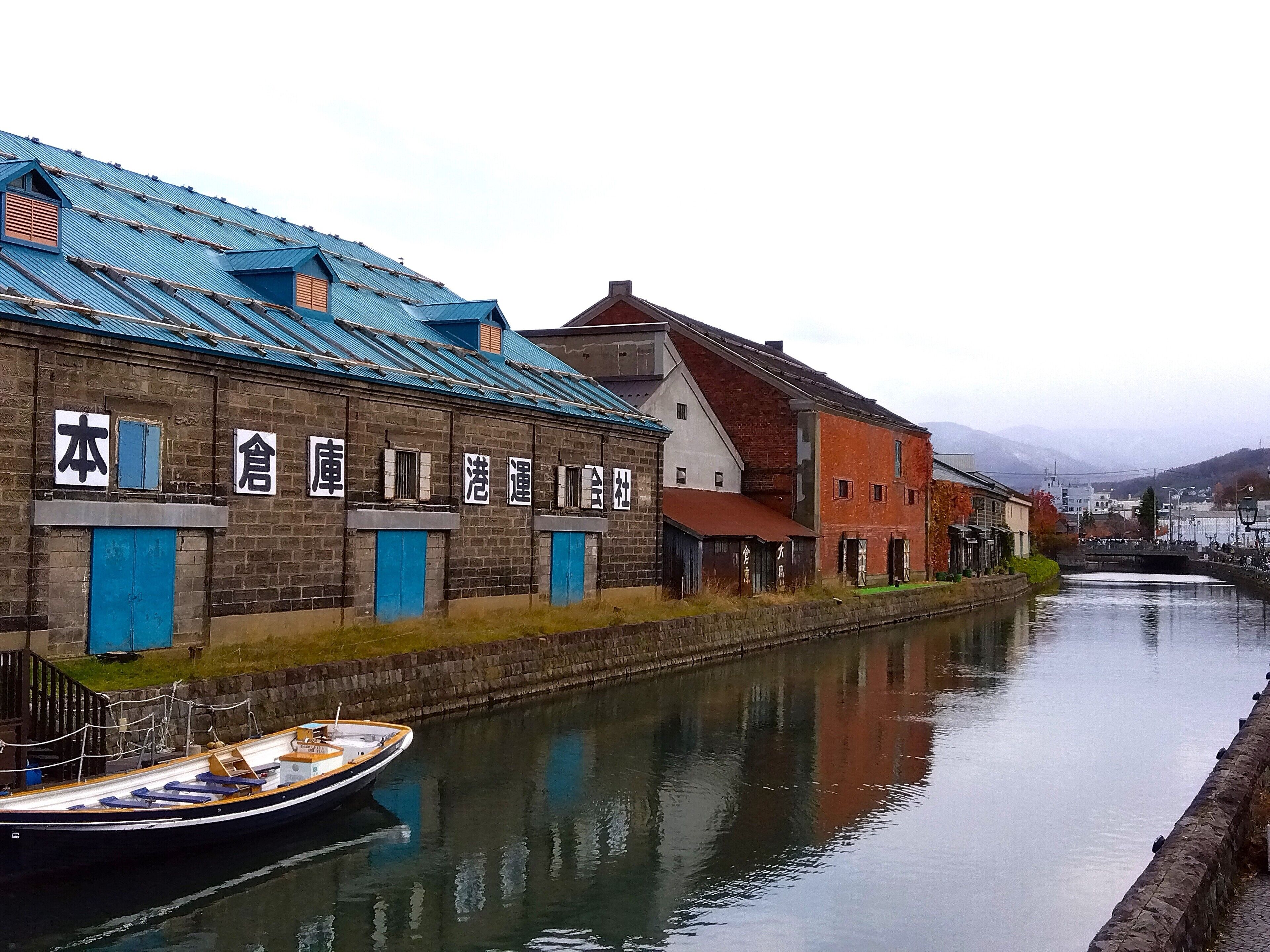 A narrow canal with traditional buildings on one side and a boat docked on the water.