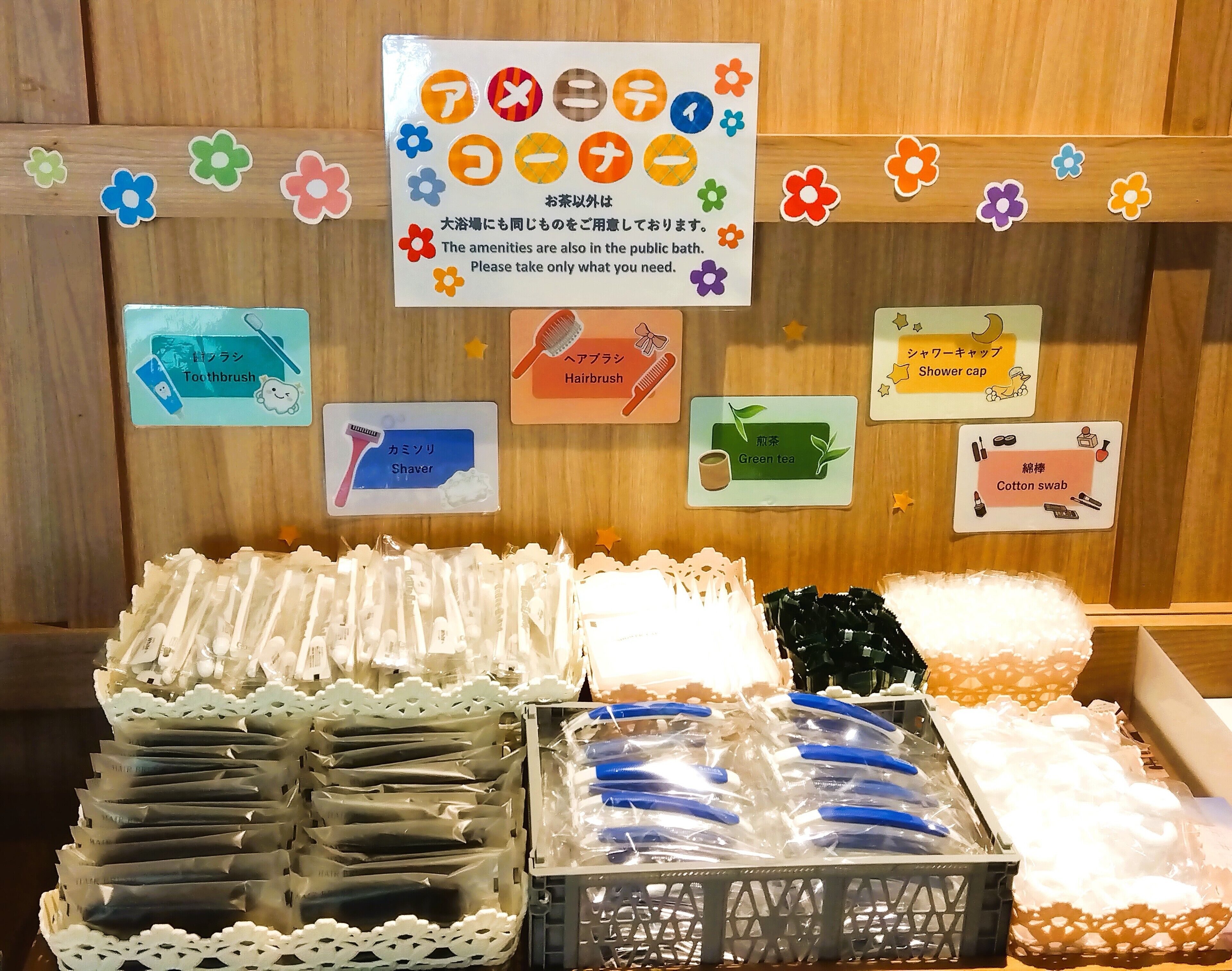 A display of toiletries with labels in Japanese, including toothbrushes, hairbrushes, shavers, green tea, and cotton swabs.