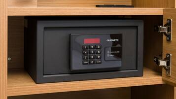 A black safe with a numeric keypad and a digital display, housed in a wooden cabinet with a metal latch.