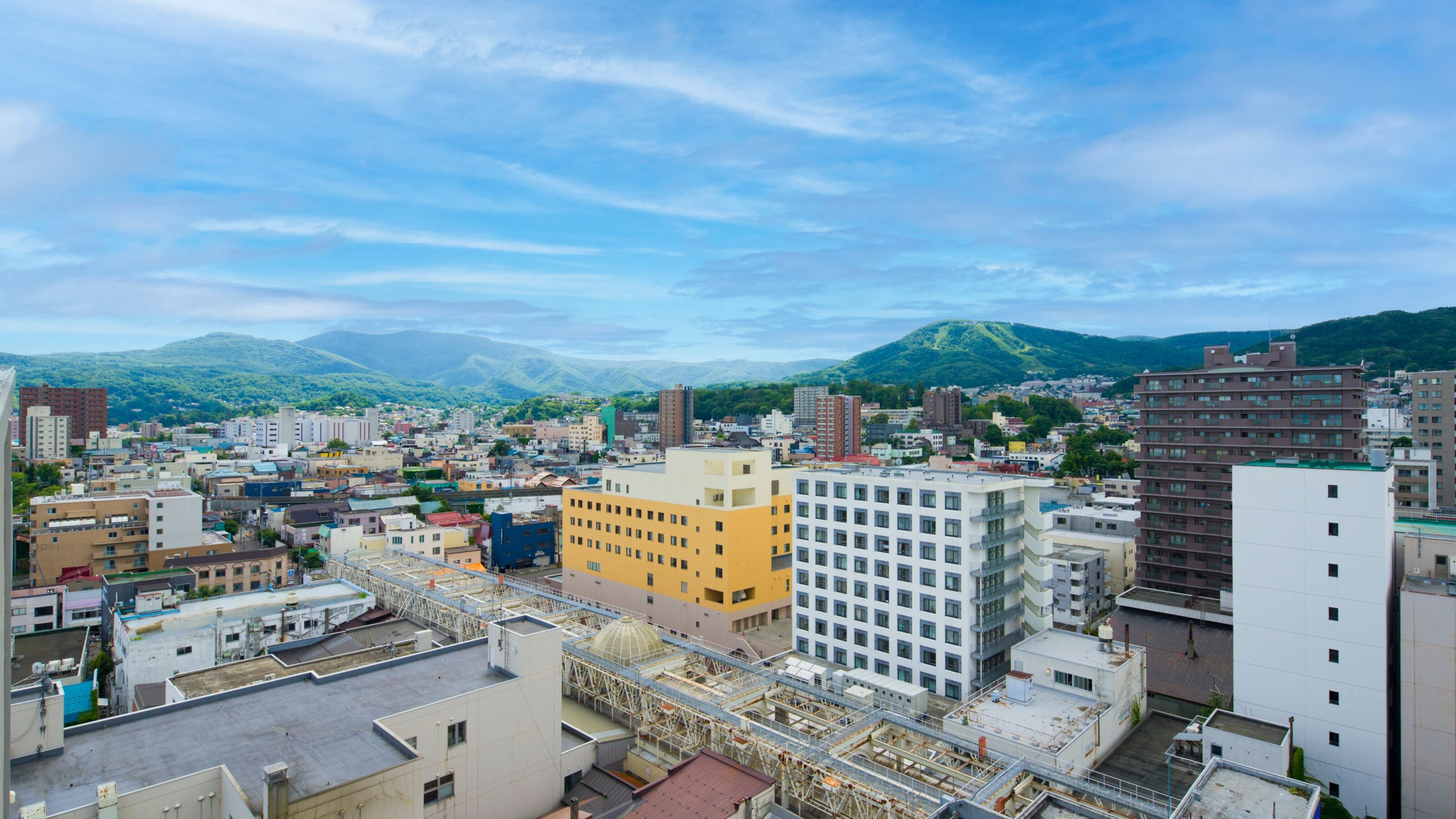 A cityscape with various buildings, including a prominent yellow building and a white building with a grid of windows.