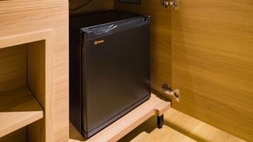 A compact black refrigerator with a Wellnay logo, installed in a wooden cabinet with a metal latch.