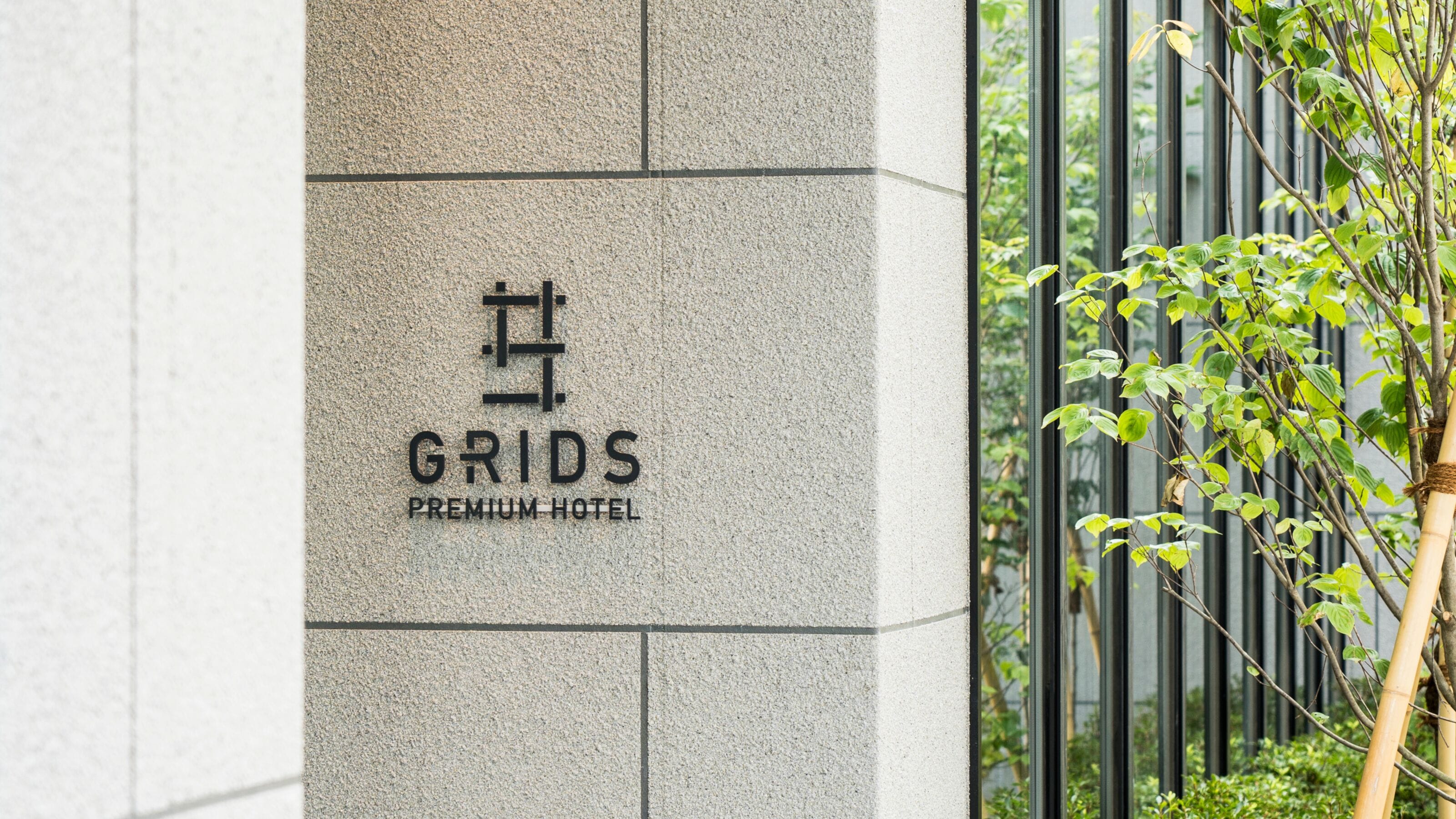 A hotel sign with the name "Grids Premium Hotel" on a textured wall.
