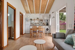 A modern kitchen with wooden cabinets, a dining area with a table and chairs, and a grey sofa. - Chalet "Casa Maran" with Pool, Wi-Fi, Garden & Terrace (Zahora)