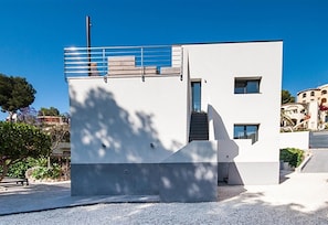 A modern building with a flat roof, a staircase leading to an upper level, and a small balcony.
