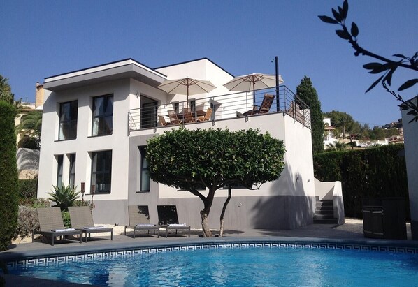 A modern two-story building with a swimming pool, outdoor seating, and a large tree. - Villa "Lynn" in Benissa Next to Mora with Mountain View, Pool & Wi-Fi (Benisa)