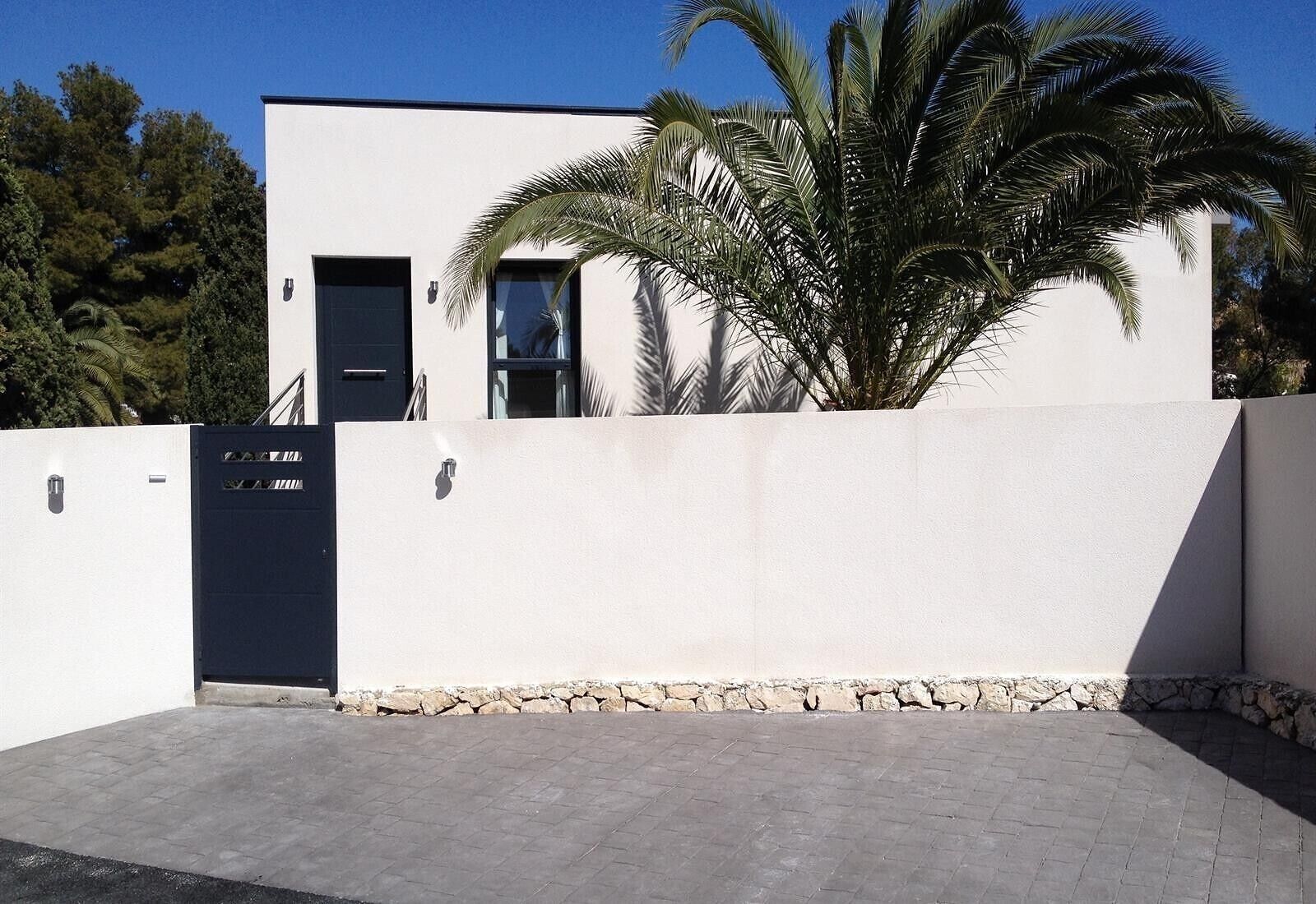 A modern building with a white facade, a black door, and a stone base.