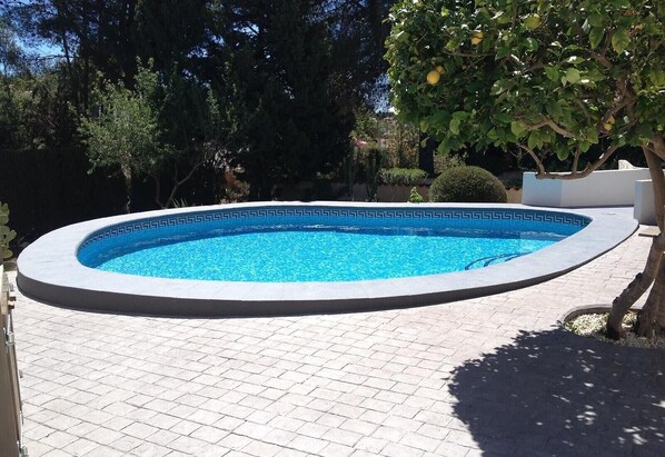 Une piscine ronde dont le bord est orné d’un motif, entourée d’une terrasse dallée.