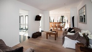 Un salón amplio con sofá, mesa de centro y televisor instalado en la pared.