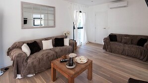 Un salón amplio con dos sofás, una mesa de centro y un espejo grande en la pared.