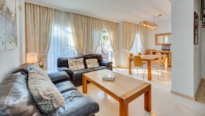 Una sala de estar moderna con un sofá de cuero, una mesa de centro de madera y un comedor con mesa y sillas.