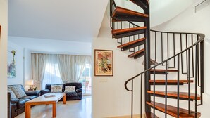 Una sala de estar con una escalera espiral, un juego de sofá y una mesa de centro.