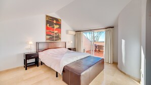 Un dormitorio con cama, mesita de noche, aire acondicionado instalado en la pared y vista a un patio exterior.