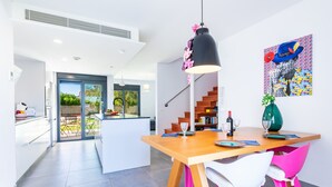 A modern kitchen with a wooden table, white chairs, and a pendant light. - Villa Puerto Blanco close to the Beach with Pool & Wi-Fi (Vinaròs)