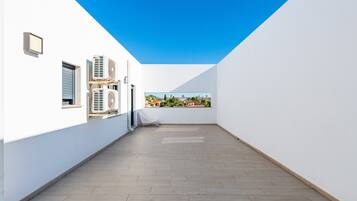 A rooftop terrace with a clear view of the city, white walls, and multiple air conditioning units.